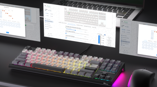 Mechanical keyboard with RGB lighting on a desk with multiple computer monitors.